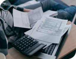 Man reviewing financial papers and using a calculator and laptop computer