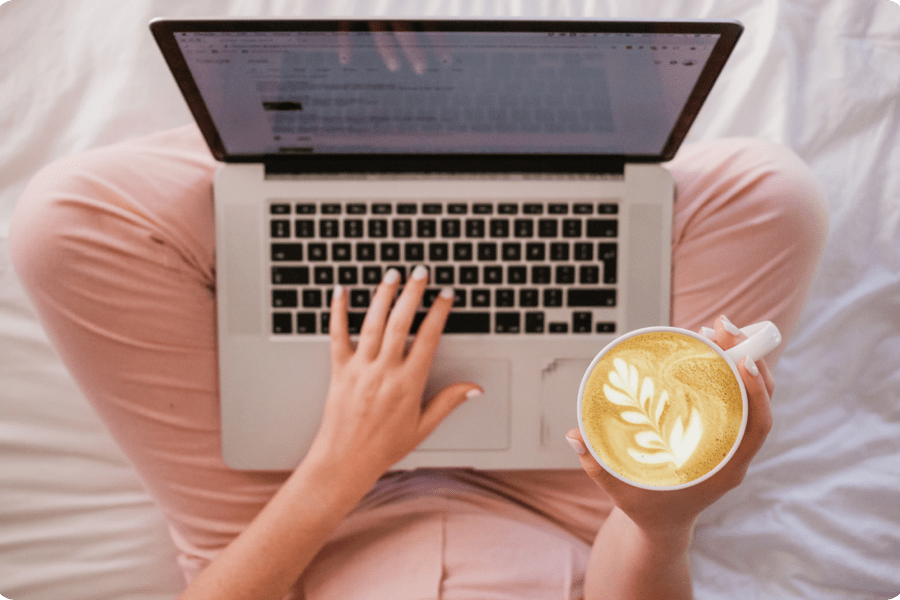 Woman using a laptop computer and holding a cup of coffee