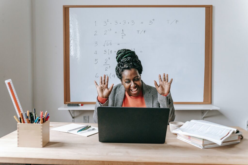 Teacher in front of whiteboard using a laptop computer